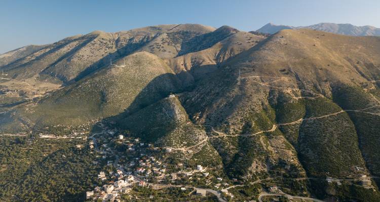 Luftaufnahme einer bergigen Landschaft mit kleinen Siedlungen.