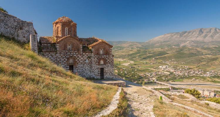 Eine alte Kirche mit Blick auf ein Tal und Berge.