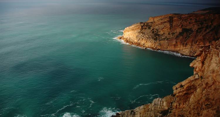 Kliffen die uitkijken over de oceaan met helder blauw water.