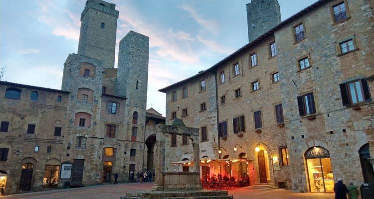 Historical town square with stone towers and evening lights.