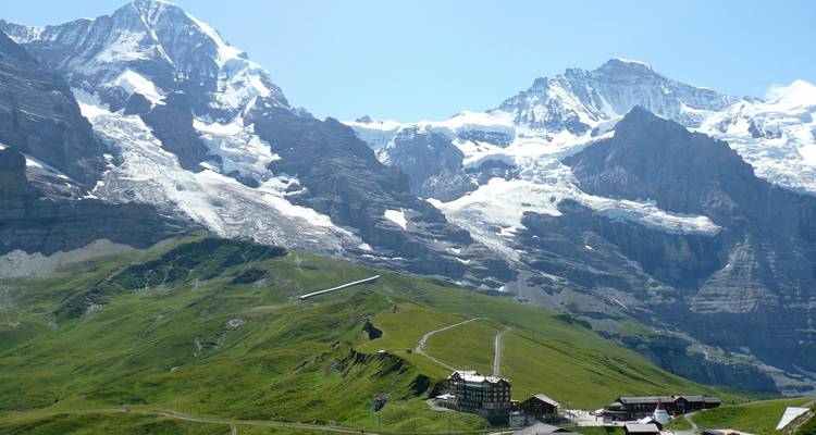 Majestueuses montagnes enneigées avec des collines vertes en contrebas.