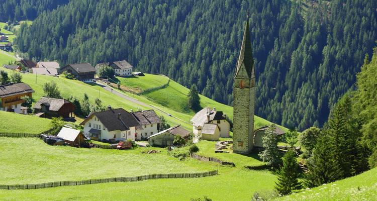Village pittoresque dans une vallée verdoyante avec un haut clocher d'église.