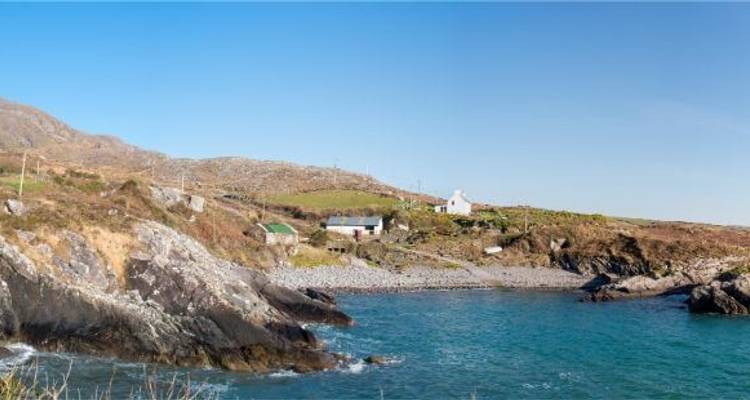 Een rotsachtige kustlijn met een verre horizon en blauwe luchten.