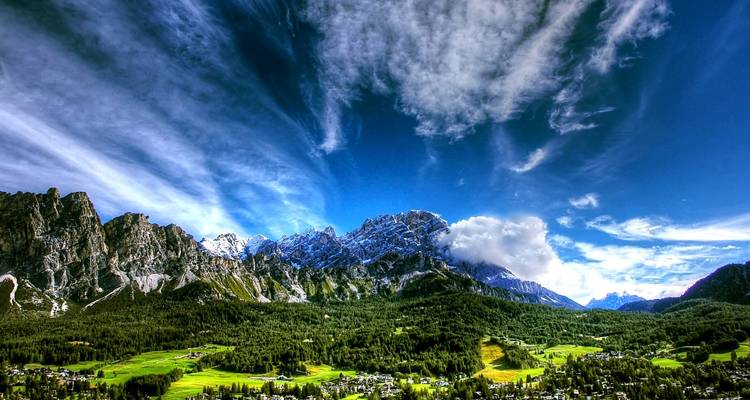 Imposante Panoramaaussicht über das Tal von Cortina d'Ampezzo mit dramatischen Dolomitengipfeln und einem dynamischen Himmel.
