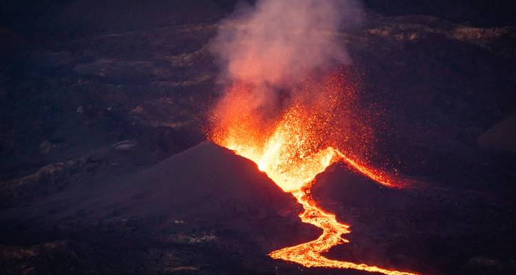 Volcan en éruption avec un coulée de lave qui s'écoule.