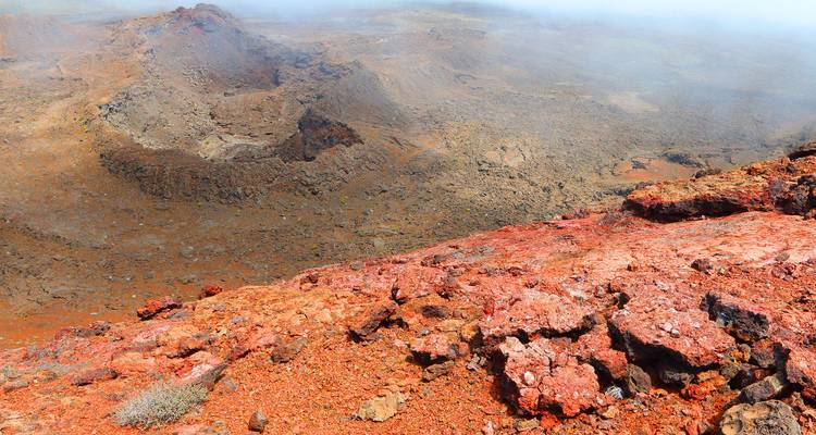 Paysage volcanique avec des roches rouges et des cratères.