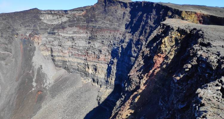 Cratère volcanique profond avec des parois rocheuses stratifiées.