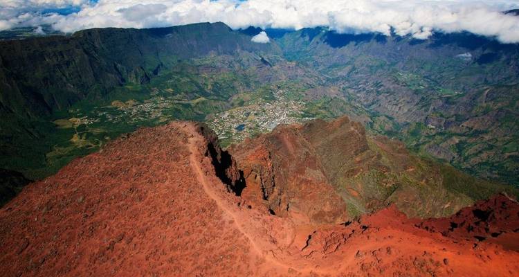 Vue aérienne d'un paysage volcanique avec des vallées et des nuages.