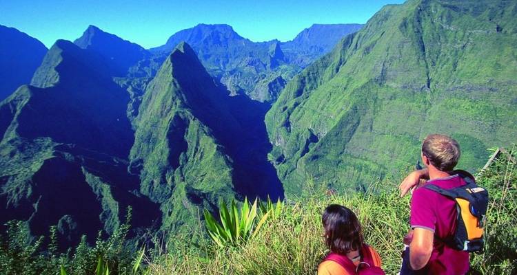 Deux randonneurs contemplant un paysage montagneux verdoyant.
