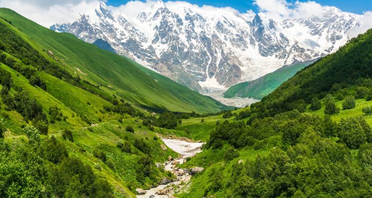 Valley with a river running through lush green mountains.
