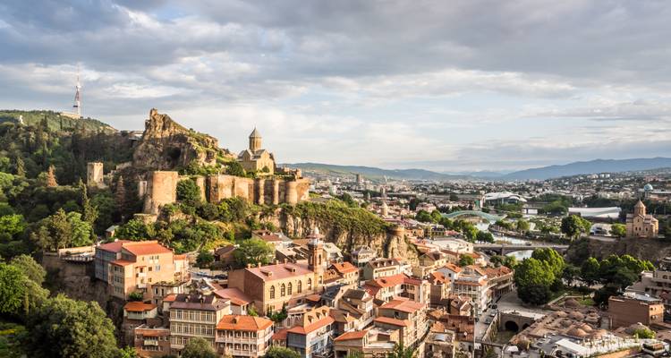 Panoramic view of Tbilisi with historic buildings and a church on a hill.