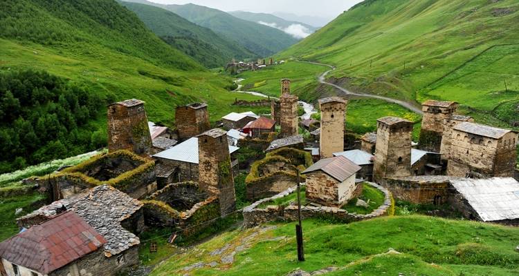 Traditional village with defensive towers in a lush valley.