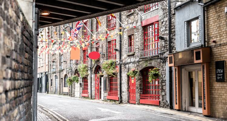 Charmante rue européenne avec des bâtiments en pierre et des drapeaux colorés au-dessus.