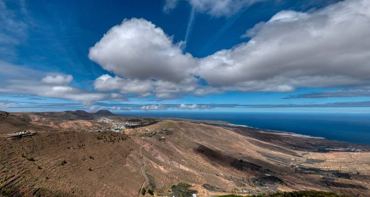 Vue panoramique sur les collines and l'océan sous un ciel nuageux.