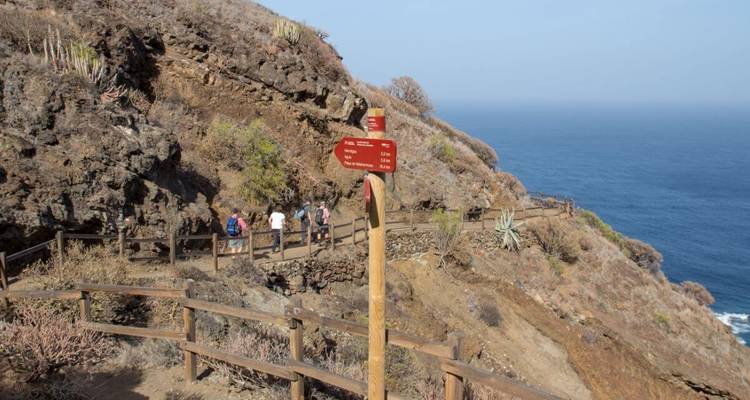Sentier de randonnée avec un panneau indicateur et plusieurs personnes qui marchent.