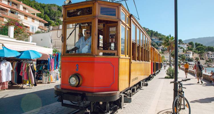 Tramway historique circulant dans une rue avec des magasins et des gens.
