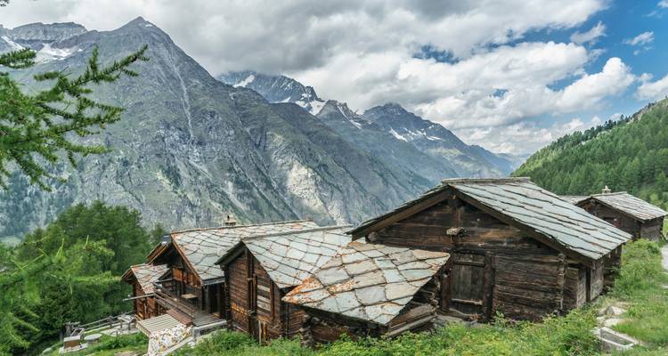 Chalets de montagne sur fond d'Alpes escarpées.