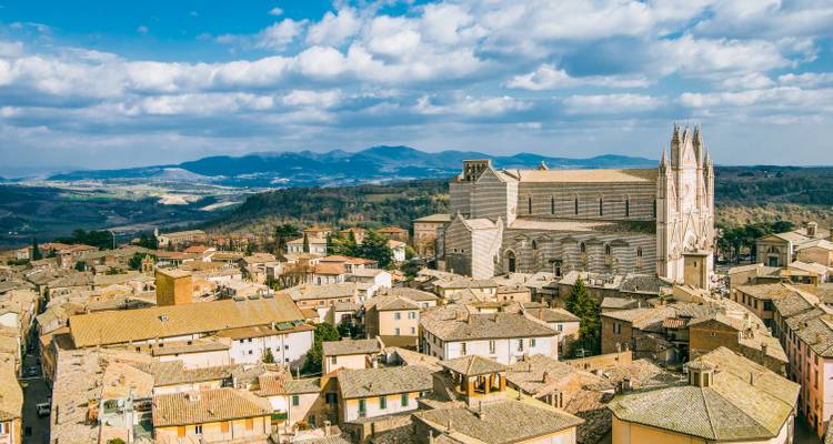 Vista panorámica de los tejados medievales de Orvieto dominados por la ornada catedral con las colinas ondulantes de Umbría de fondo.