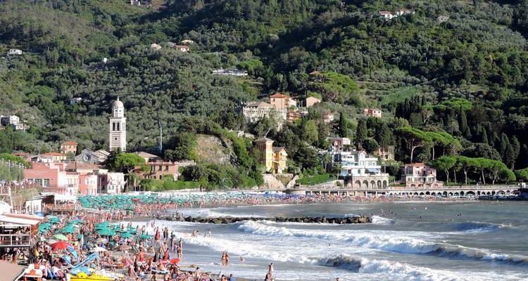 Popular beach with people and colorful umbrellas.