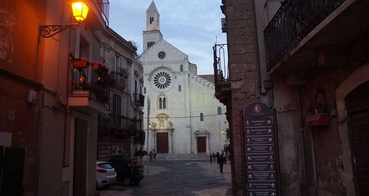 Smalle straat met een oude kerk en mensen in de verte.