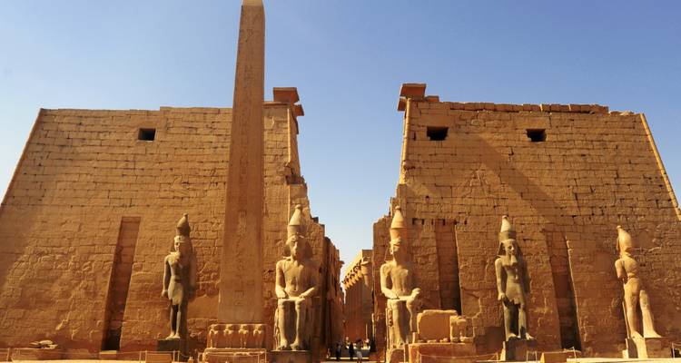 Ancient temple entrance with giant statues and hieroglyphs.
