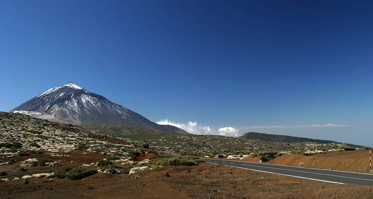 Route panoramique menant à une montagne enneigée sous un ciel bleu.