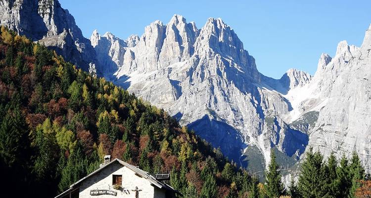 Alpine Landschaft mit einer Berghütte und aufragenden Gipfeln.