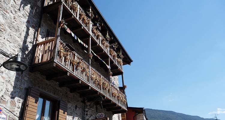 Edificio de piedra con balcones de madera y plantas colgantes.