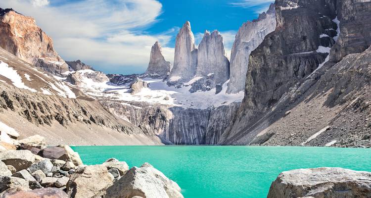 Paysage montagneux avec un lac turquoise et une personne admirant la vue.