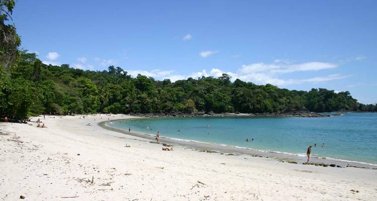 Plage spacieuse avec des gens qui nagent et se détendent.