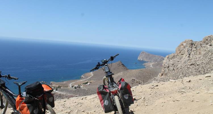Vue côtière avec bicyclettes et terrain rocheux surplombant la mer.