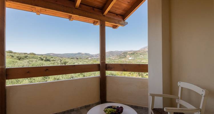 Überdachte Terrasse mit Sitzgelegenheiten und Blick auf die Hügel.