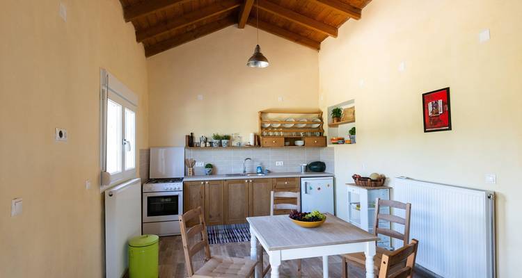Kücheninterieur mit Tisch und Stühlen, dekoriert mit Obst und Pflanzen.
