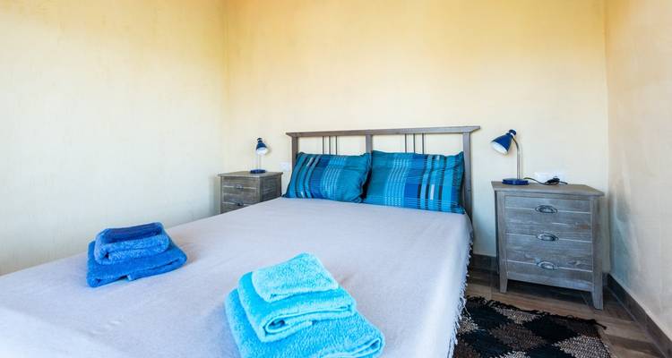 Slaapkamer met een opgemaakt bed en gevouwen handdoeken erop.