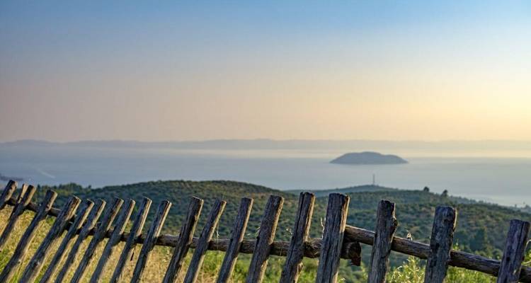 Une vue panoramique d'une clôture surplombant la mer au coucher du soleil.