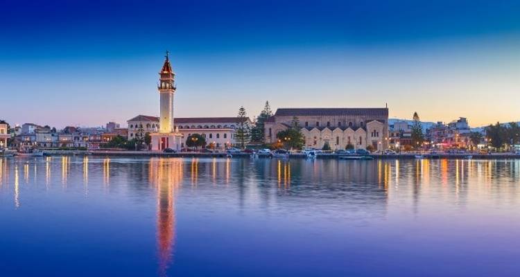 Port et bâtiment historique illuminés au crépuscule avec reflets sur l'eau.