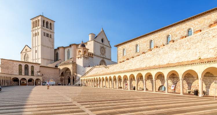 Place avec basilique historique et arches sous un ciel dégagé.