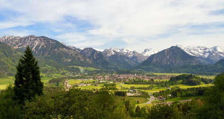 Talstadt umgeben von üppigem Grün und Bergen.