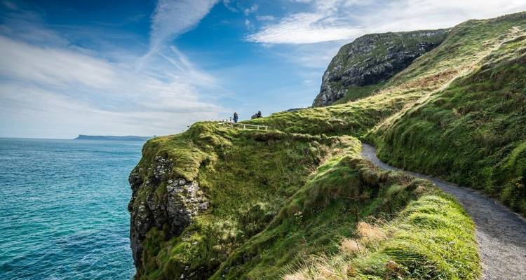 Sentier le long des falaises herbeuses surplombant l'océan, avec des gens qui marchent.