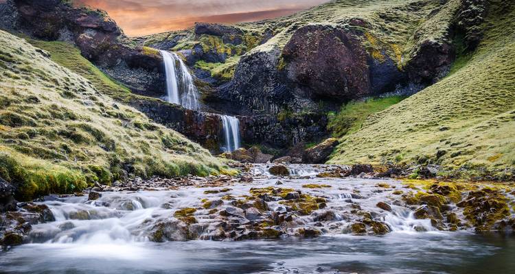 Kleiner Wasserfall, der durch felsiges Gelände fließt.