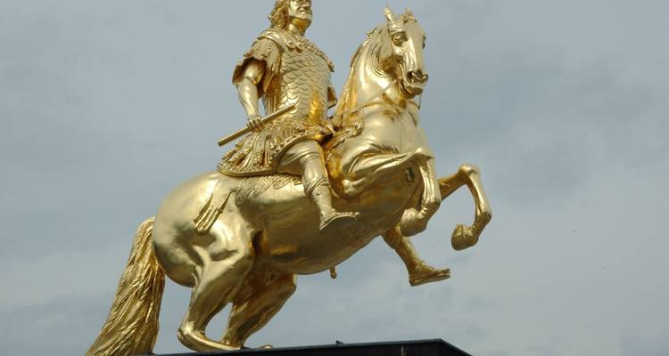 Une statue équestre dorée sur fond de ciel nuageux.