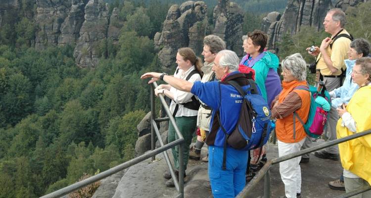 Un groupe de touristes observant une vallée pittoresque depuis un point de vue.