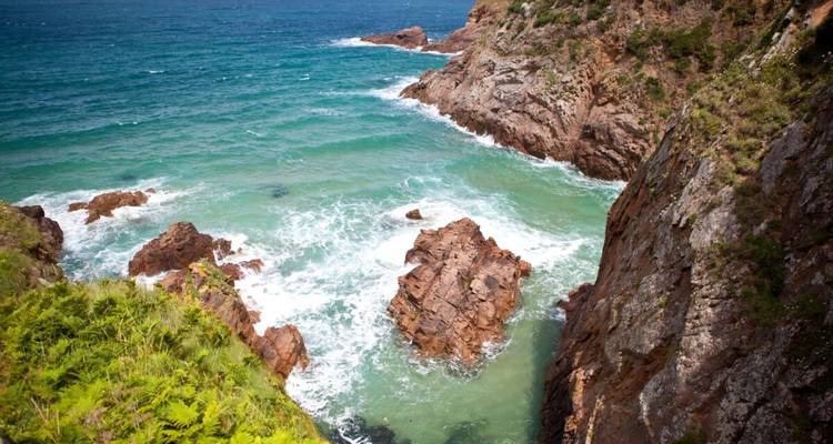 Falaises rocheuses escarpées avec des vagues écumantes qui se brisent en contrebas.