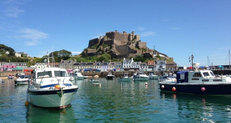 Port avec des bateaux et un château historique sur le littoral.