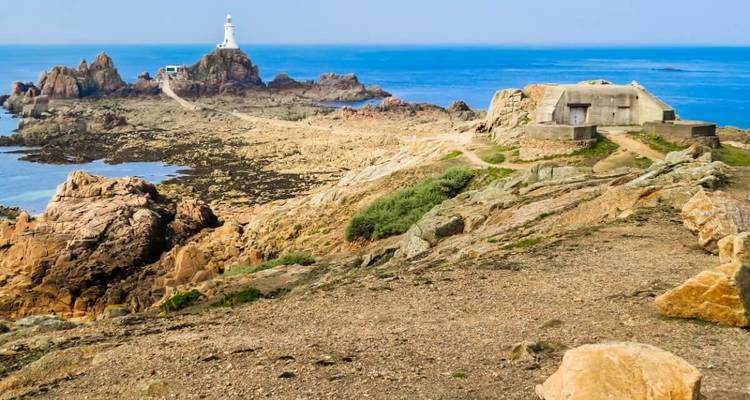 Vue pittoresque d'un phare sur un paysage côtier rocheux.