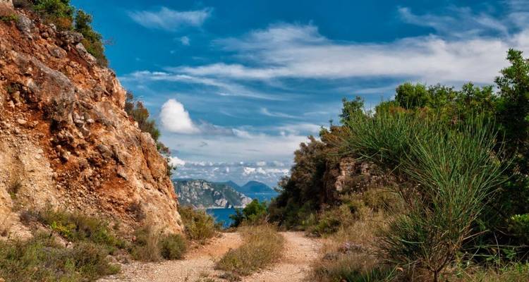 Paysage côtier avec sentier rocheux et vue sur l'océan.