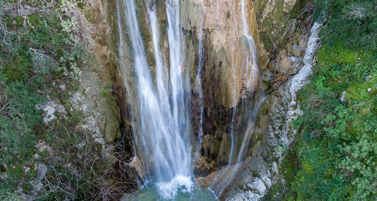 Waterval die over rotsen naar beneden stroomt, omgeven door groen.