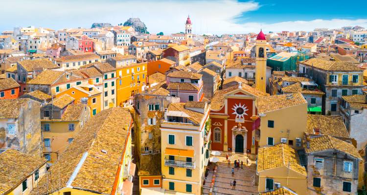 Kleurrijke daken van een historische stad onder een blauwe hemel.