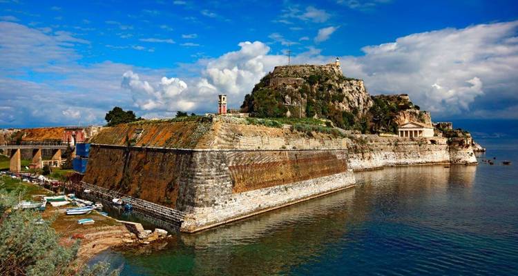 Forteresse historique surplombant la mer avec un ciel bleu.