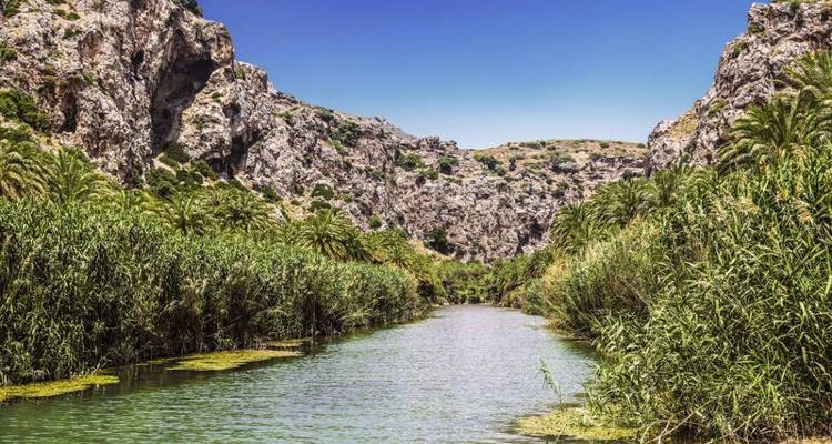 Schilderachtige rivier die door een weelderige vallei met rotsachtige heuvels stroomt.